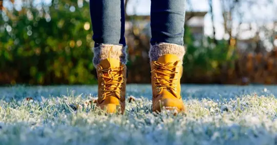 Feet in orange shoes standing on frozen grass