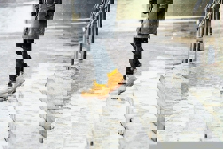 A person in work boots carefully walks on steps covered in snow