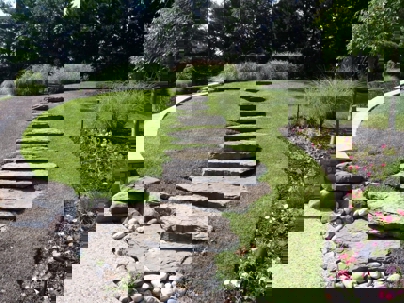 A decorative rock staircase leads up a green hill.