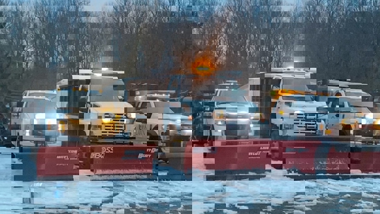 Commercial snow removal: Three trucks with plows, facing forward, ready for a snowstorm