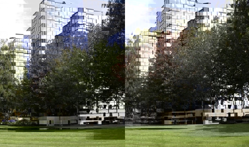 A modern glass office building is nestled in a green lawn.