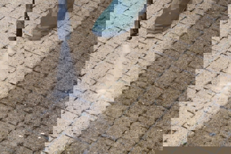 A person power washes a dirty brick patio