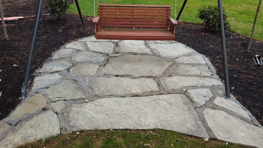 stone patio landscape enhancement with swing