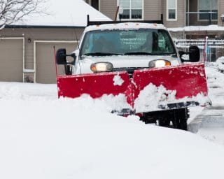 A snowplow works hard to clear snow from a driveway. 