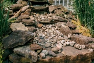 A professionally built rock waterfall feature in an outdoor landscaping project.