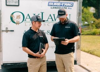 Two Oak Lawn Landscaping contractors are reviewing plans on a tablet.