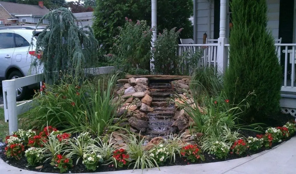 rock waterfall is surrounded by lush foliage in a well-maintained garden