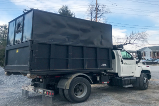 Here is a black OakLawn Landscaping dump truck on a gravel surface.