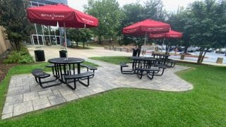 Patio space with three red umbrellas and tables with built in benches