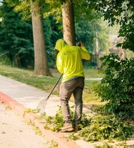 Landscaping worker rakes debris from a curb