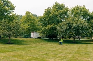 Employee in uniform walks the property next to their service trailer
