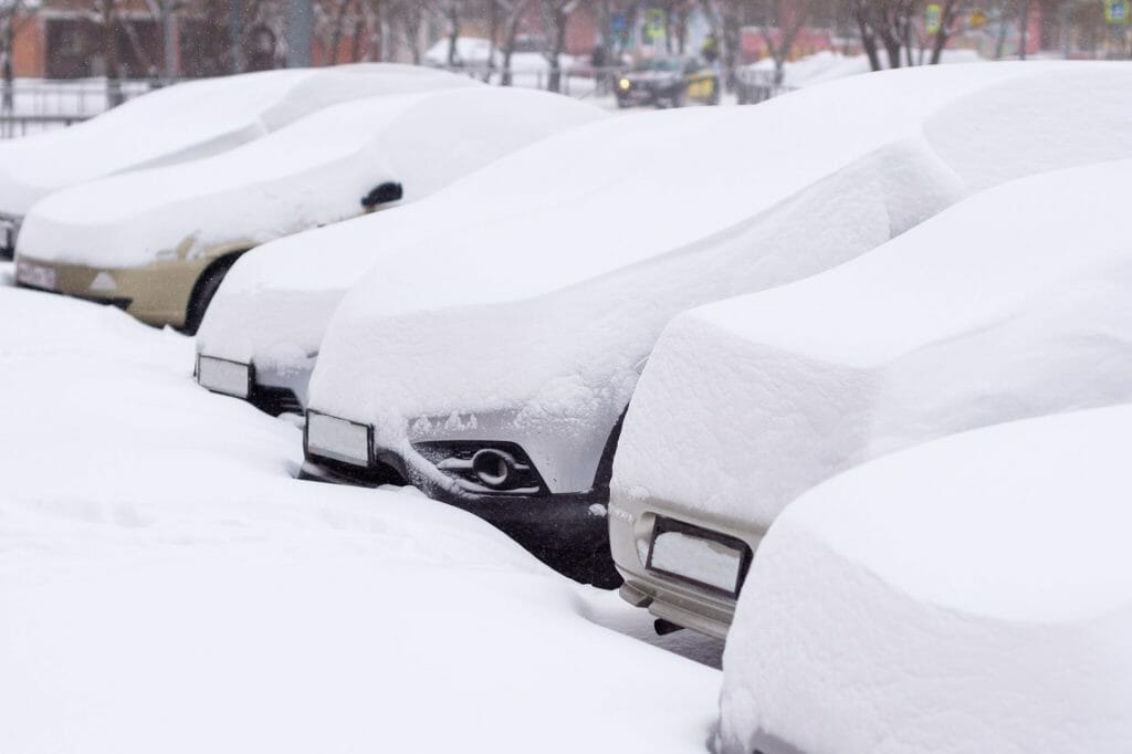 Cars are covered in deep snow, in a row, showing the risks of not investing in snow removal