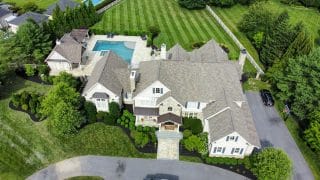 Aerial view of a manicured lawn and landscaping surrounding a large luxury home